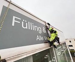 Kletterer montiert Werbeschild an Fassade